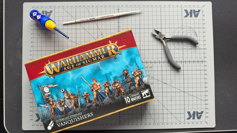 A box of Vanquishers on a cutting mat with the essentials beside it: clippers, a file and a tube of plastic glue.